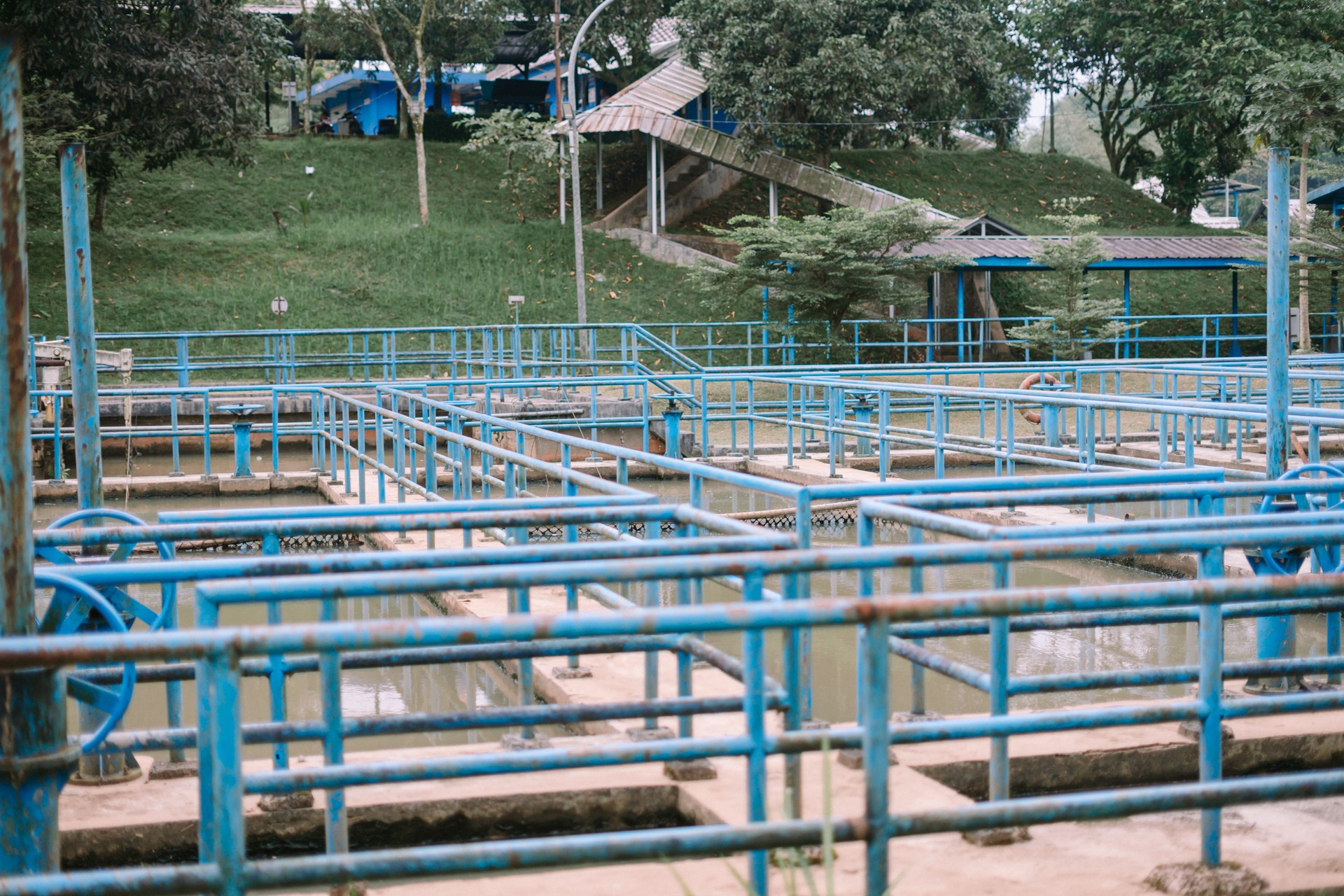 Estação de tratamento de águas residuais com corrimãos azuis e pano de fundo verde